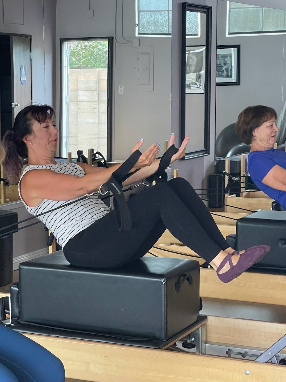 A client pulling straps into a teaser position on the reformer
