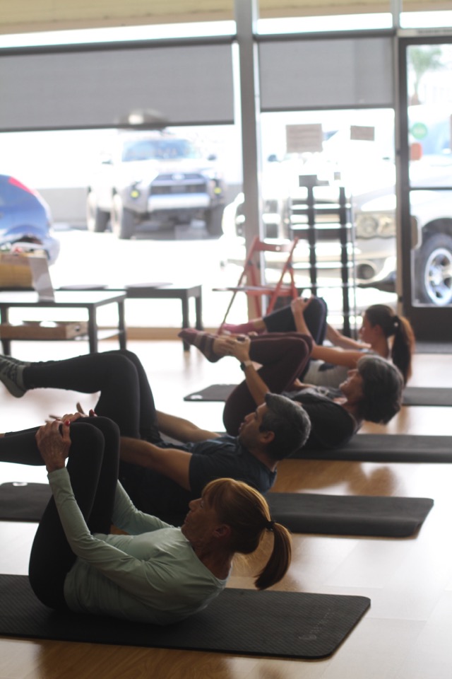 A mat class rolling through a teaser exercise together