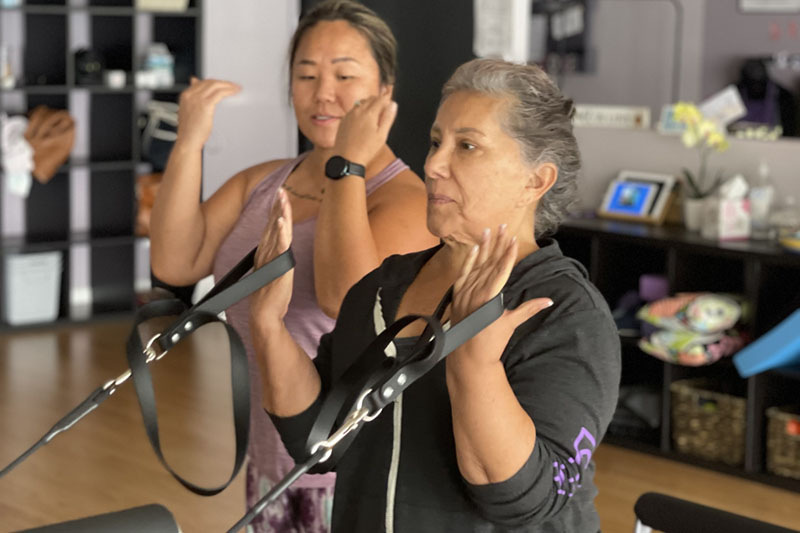 An instructor guiding a new client through their first reformer session